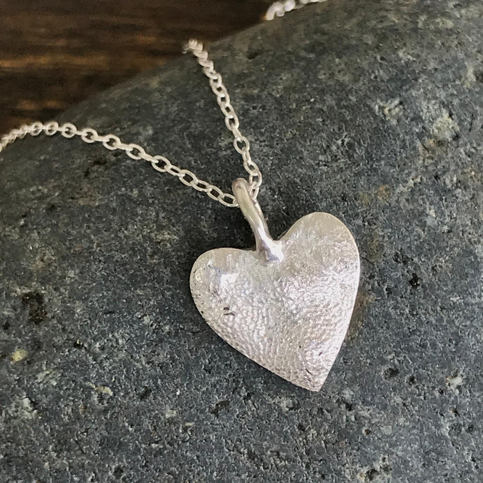 Close-up of a silver paw print pendant showing fine print texture and polished finishing