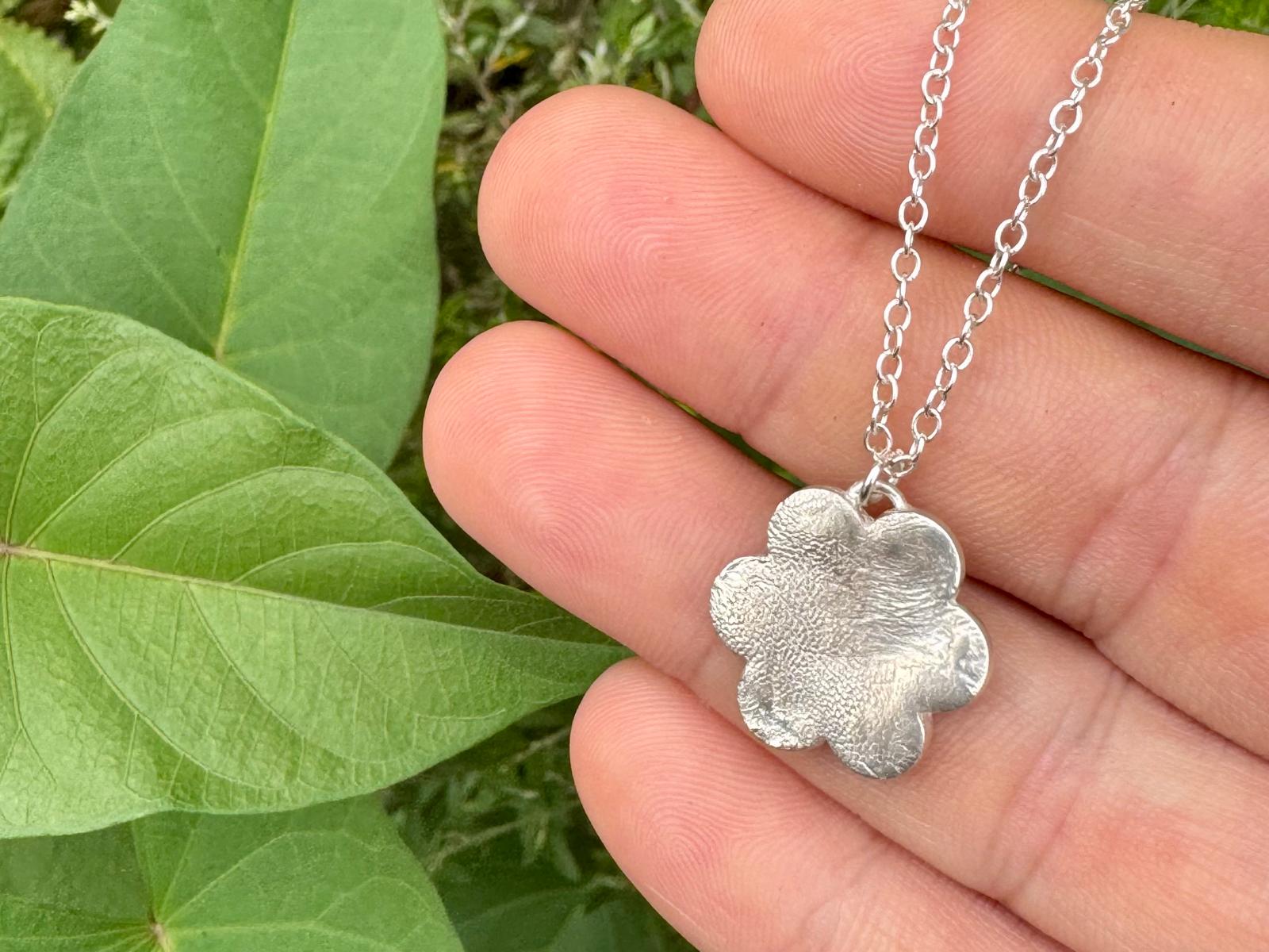 Close-up of a heart-shaped pendant showing fingerprint and pawprint texture